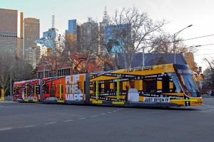 An E Class Tram with Flip the Vape messaging moving away from the city, skyline in the background.