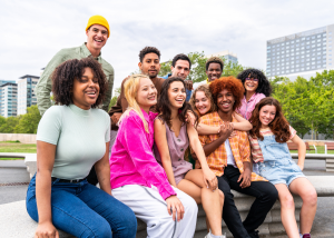 Yeates Family Consulting Expands Comprehensive Mental Healthcare Access with Digital Innovation 17 A happy, diverse group of teenagers and young adults gathered together outdoors on steps with city buildings visible in the background.