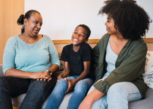 A family therapy session showing a mother, young child, and female therapist sitting together on a couch in a comfortable counseling office.