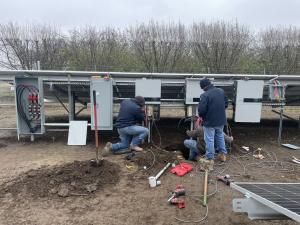 A1 Contractors installing a ground-mounted solar power system with inverters.