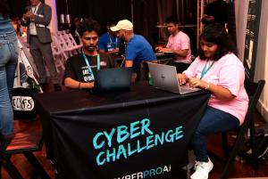 CyberproAI is proud to announce a new collaboration with the Missouri Cybersecurity Center of Excellence (MCCoE), a nonprofit based in Springfield dedicated to building and sustaining a resilient cybersecurity workforce in Southwest Missouri Two students sitting on a table with laptops engaged in a CTF event in a hall of a cyber conference in NYC