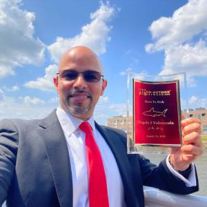 Engels J Valenzuela, Award-Winning Author, holding his Born to Risk recognition in Philadelphia