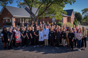 staff posing for group photo outside in front of the building