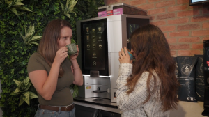 Employees enjoying cups of &BACK COFFEE in front of a bean-to-cup machine in a corporate office.