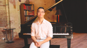 Melbourne Pianist Calvin Leung sits in front of a grand piano at Bakehouse Studios