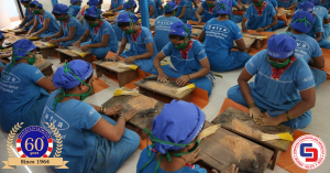 Women workers in blue uniforms hand-rolling Satya incense sticks in Mumbai factory, showing traditional masala incense production process.
