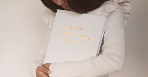 Glimmery Moment New generation holding Our Family’s Table seasonal recipe journal, symbolizing offline living and everyday magic.