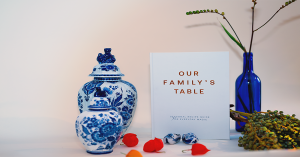 Our Family’s Table seasonal recipe journal on a table with Delft blue ceramics, berries, and flowers, symbolizing Dutch culinary heritage and seasonal offline living.