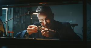 Portrait close up of a professional watchmaker repairer working on an old vintage pocket watch in a workshop.