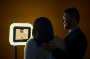 Couple giving an interview on camera, facing the video booth with the on-screen prompt "What are your words of advice for the newlyweds?"