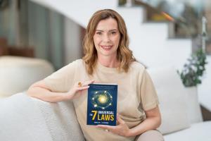Monica Ion holding her new book, The 7 Universal Laws