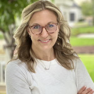 Portrait of Shaunda Zilich, newly appointed Chief Marketing and Customer Officer at The Martec. She is smiling, wearing glasses and a light top, standing outdoors with greenery in the background.