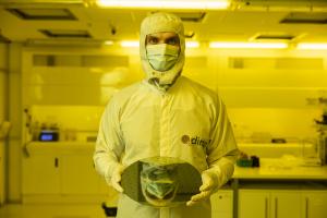 Diraq Measurement Engineer Paul Steinacker standing in a laboratory and holding an imec silicon wafer containing quantum computer chips