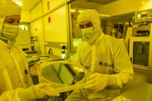 Diraq Fabrication Manager, Fay Hudson, and Diraq Measurement Engineer, Paul Steinacker, in a laboratory, holding a silicon wafer containing quantum computer chips