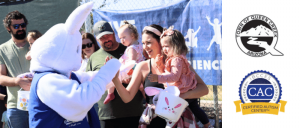 A costumed bunny greets children and families at a community event, surrounded by festive banners and an enthusiastic crowd.