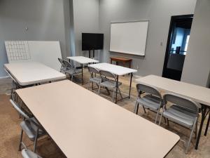 New classroom at Salt and Light Academy with tables, chairs, and a whiteboard, representing ongoing growth and community support for tuition-free education.