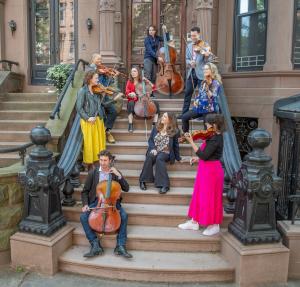 Pianist Simone Dinnerstein and members or her ensemble Baroklyn casually standing outside a Brooklyn brownstone