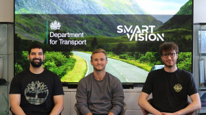 Photo of the SmartVision team sitting in front of a screen displaying the SmartVision and DfT logos.