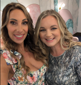 Kristine Bene standing with Lise Reitsma at a Prosperity Of Life event in Australia, smiling and enjoying the community atmosphere.