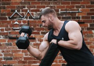 Man doing a preacher curl on a bench while using a pair of Evolve Grips ergonomic gym grips