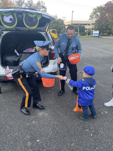 Police officers giving candy to a young child dressed as a police officer at Bierman Autism Centers’ Trunk-or-Treat event.