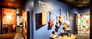 A colorful exhibition featuring various guitars, instruments, and informative panels titled