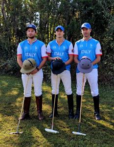 three teammates stand next to each other in polo equipment
