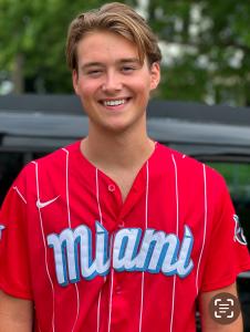 Boy with blonde hair wearing red Miami University jersey smiling