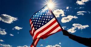 Mona Shah, Esq. and Sam Bayat, Esq U.S. flag on the Sun background, symbolizing security, opportunity and stability. Invitation to join Bayat Group’s seminar in Dubai on the EB-5 Visa and VOCO Times Square project.