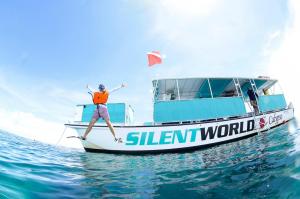 Silent World Dive Center , a dedicated marine operator in the Florida Keys, has achieved the prestigious TripAdvisor Top 1% Award, an elite designation that ranks it among the world’s most outstanding guest experiences Action shot of a snorkeler in an orange life vest leaping happily from the side of the teal and white Silent World Calypso, a 51-foot Corinthian catamaran, into clear, shallow Key Largo water.