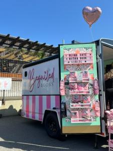 Beguiled Books renovated cargo trailer with pink and white stripes on a sunny day