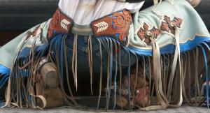 Rodeo cowboy shown from behind and crouching in ornamented chaps