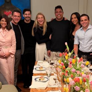 Rony Jabour, Carolline Jabour, Ronaldo Nazário, Celina Locks, and friends share laughter around a dinner table adorned with tulips during a Fenômenos Foundation evening in São Paulo, Brazil, October 2025.