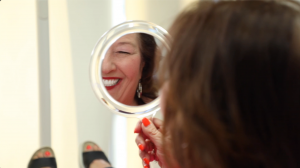 Woman smiling into a handmirror