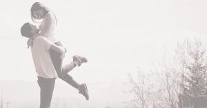 Swept Dating Launches as the First Dating App That Fights Ghosting, Catfishing, and Shallow Matches 13 A black-and-white image of a young man lifting a smiling young woman in his arms outdoors; she has one leg kicked up, and they share an affectionate gaze amid a background of bare trees and hazy sky.