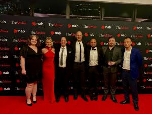 Professional photo of 7 team members of Real Estate Investment Finance (REIF), including Founder David Chehade and General Manager, Jake Sewell, standing in front of event background with The Advisor Awards and National Australia Bank logos on a black bac