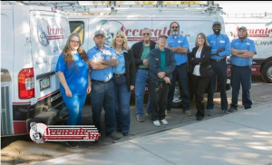 Group photo of Accurate Air team members standing in front of company service vans, wearing blue uniforms and casual attire, representing the HVAC company’s friendly and professional staff.