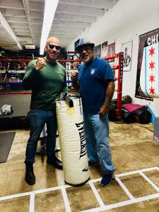 Ralph C. from Secure Locks and coach Johnny Plaza pose with a sponsored Everlast bag at the Humboldt Park Youth Boxing Gym in Chicago.