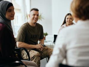 Smiling veteran in Army shirt participating in group therapy session for addiction treatment in Orange County