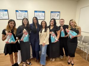 Lindenhurst High School Cosmetology students pose with Moroccan Oil products gifted to them, standing alongside their instructor Jackie Coscia, who is centered in the group.