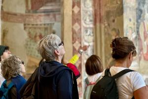 Group of visitors inside Abbazia di Santa Giustina Villa Badia Sezzadio looking at medieval frescoes during a cultural visit in Sezzadio Italy