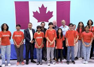 A group photo of Zebra Robotics students wearing red “Canada” shirts standing with MPP Deepak Anand and Zebra Robotics mentors in front of a large Canadian flag during the award ceremony recognizing teams advancing to the WRO 2025 Internationals.