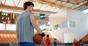 The world of college athletics is buzzing with unprecedented change Young basketball player on court with his teammates playing in background.