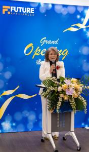 Lydia Yang standing at a podium decorated with flowers, speaking during the grand opening of Future Appliances in Richmond Hill.