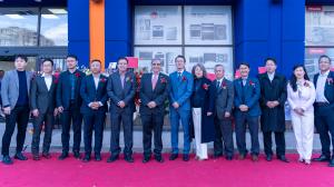 A group of executives and guests stand on a red carpet in front of the Future Appliances storefront during the Grand Opening Ceremony, posing for a commemorative photo.