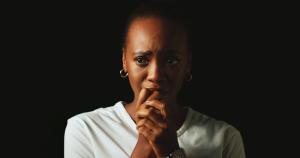 Young black woman, in a very dark room, in despair, in grief