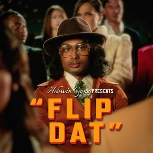 Ashwin Gane dressed as Inspector Gane in vintage noir attire, seated among a stylized audience, featured in the official cover art for his music video “Flip Dat.”
