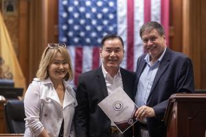 During the Chuseok K-Fest Recognition Ceremony, community leader Hyeong Reap Kim is presented with a City of Jersey City Certificate of Recognition, joined by Sylvia Kim, Chair of the HCCC Korean Chapter, and Emory Edwards, President of the Hudson County