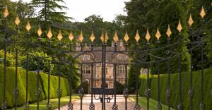 Historic manor house framed by wrought iron gates and landscaped gardens, symbolising heritage, family continuity, and long-term stewardship.