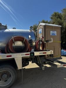 A Barrios Site Services truck with a large waste tank and a portable toilet strapped to its side.